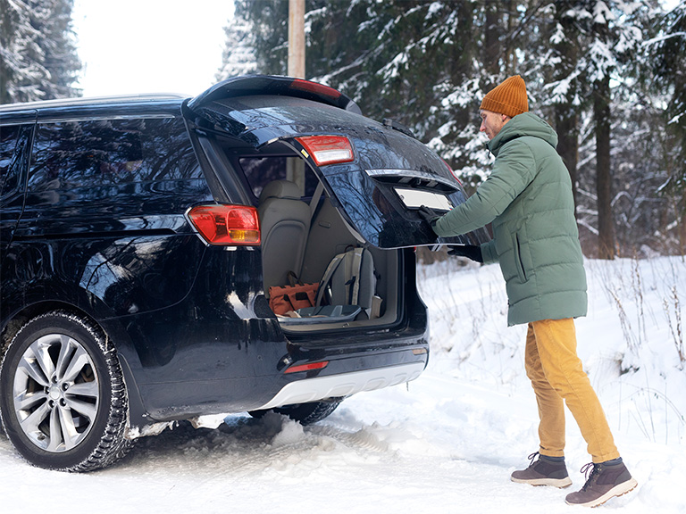 man closing suv trunk in icy weather
