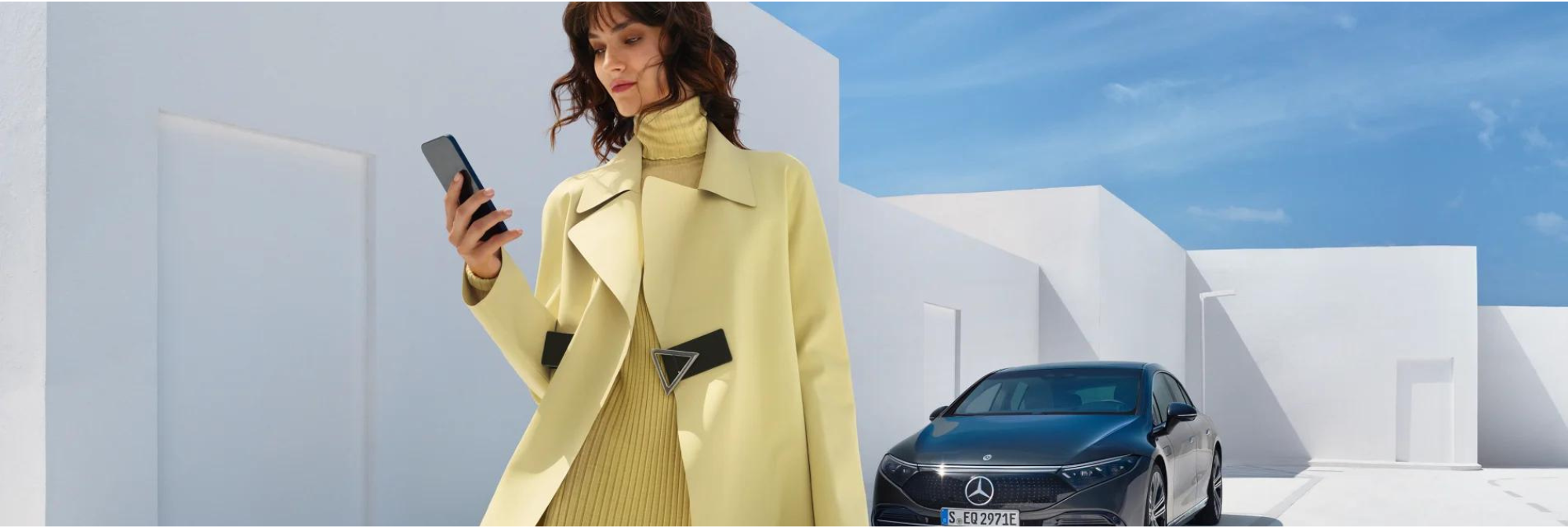 Person on phone in front of Mercedes-Benz vehicle