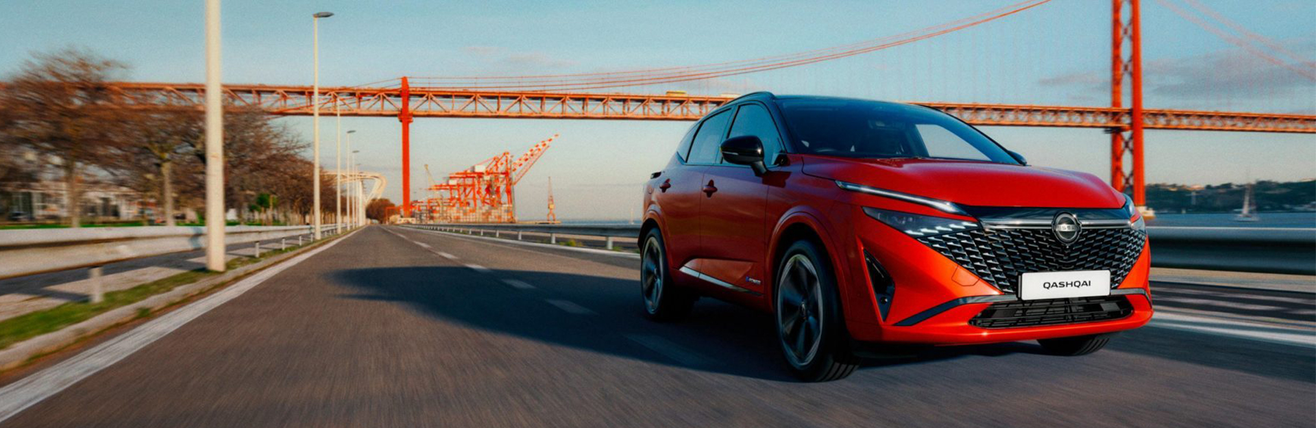 Red nissan qashqai driving next to red bridge