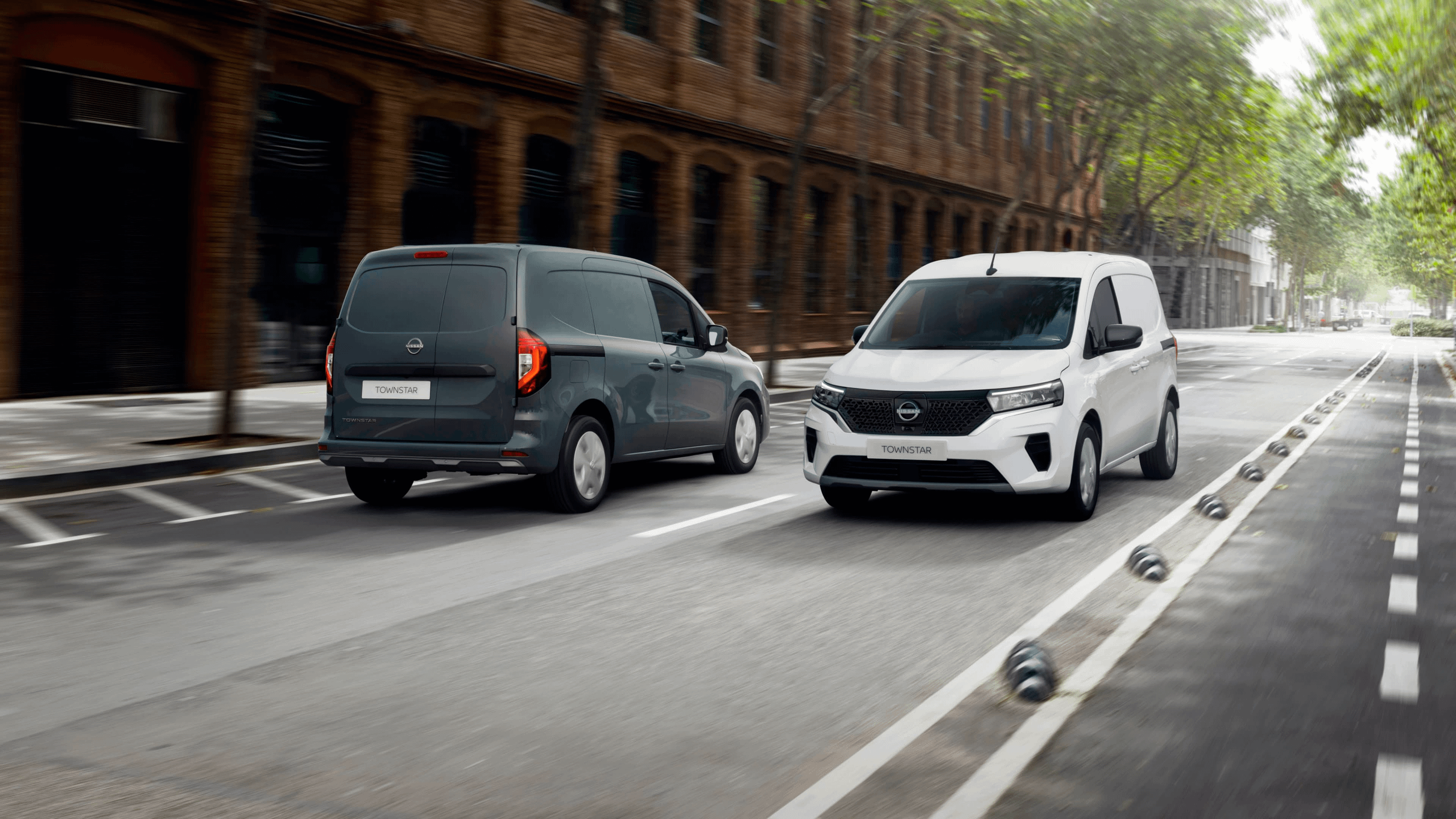 White and black Nissan Townstar vans driving in opposite directions