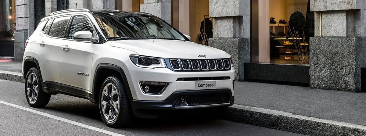 White Jeep Compass driving along road