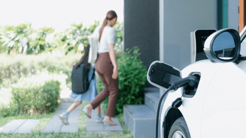 Electric car charging at home while female driver and child go into the house