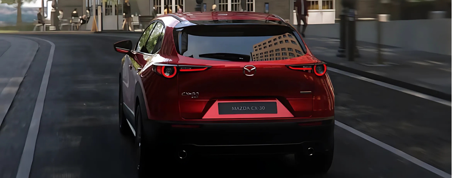 Rear view of Mazda CX-30 driving along an urban road.