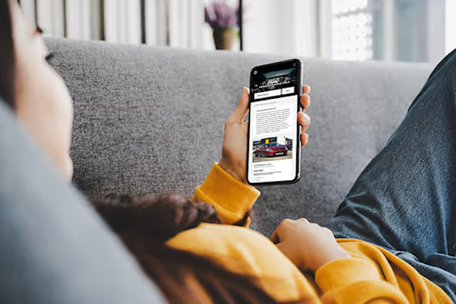 person looking up renault approved used vehicles on their phone from their sofa