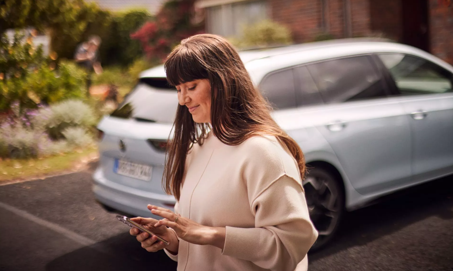 Person on smartphone next to a Volkswagen Golf Estate