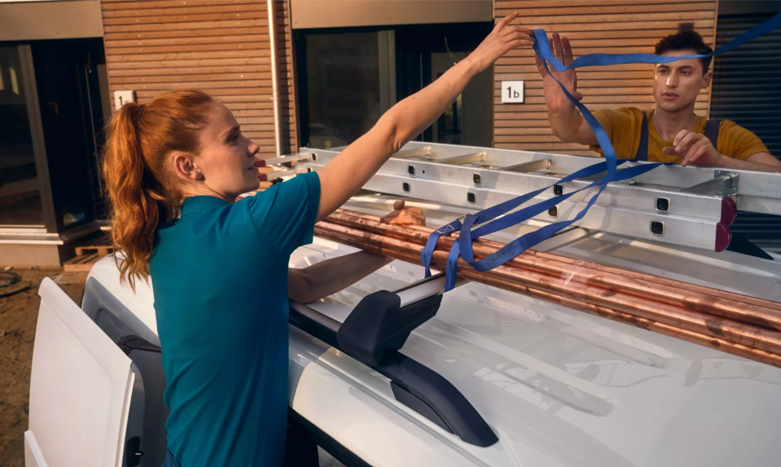 Person tying a ladder to roof of Caddy Cargo Van