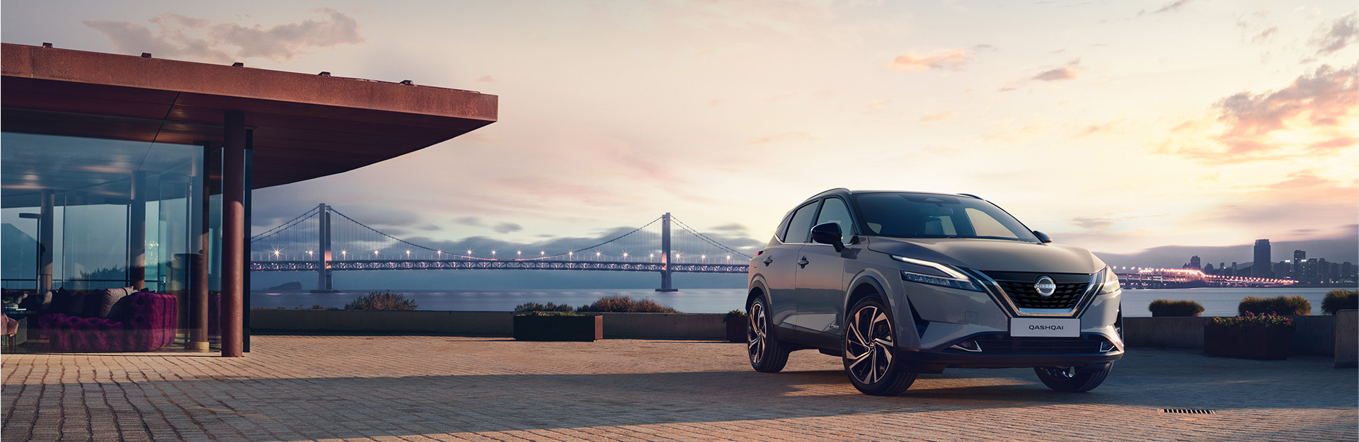 Nissan Qashqai E-Power parked on a dock at sunset with a cityscape background.