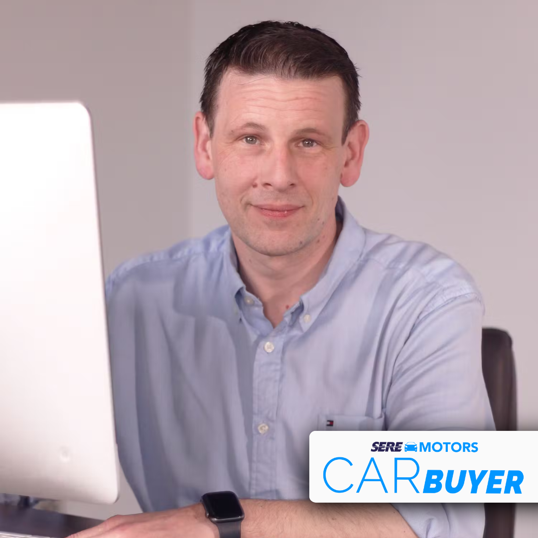 man with pale blue shirt in front of a computer