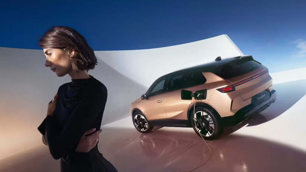 Bronze Vauxhall Grandland charging in a studio with a person standing nearby.