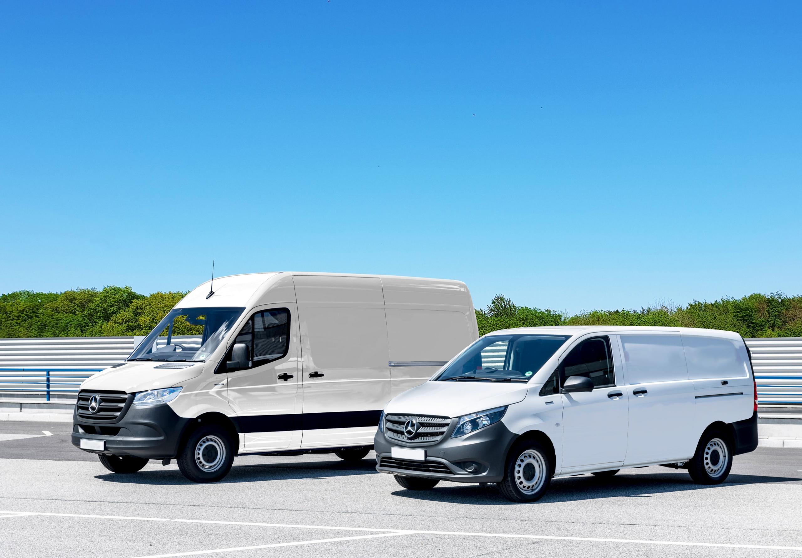 Two white delivery vans parked in a spacious parking lot under a clear blue sky