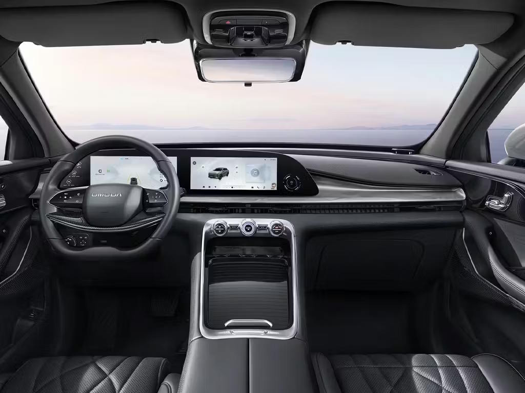 Interior dashboard view of the Omoda 9, featuring a dual-screen digital display, two-spoke steering wheel, quilted leather seats and sleek centre console with rotary controls.