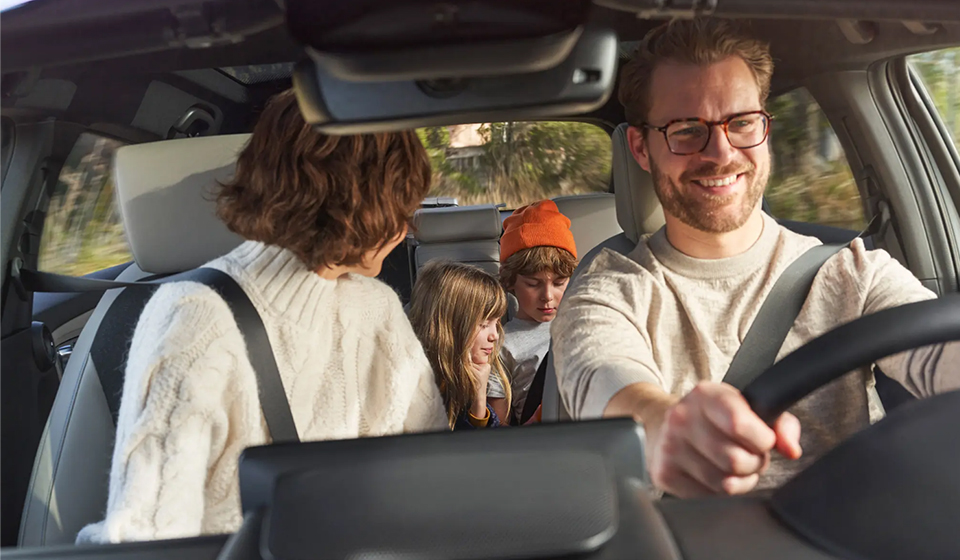 Family driving in a honda hrv on a rural road with the driver smiling.
