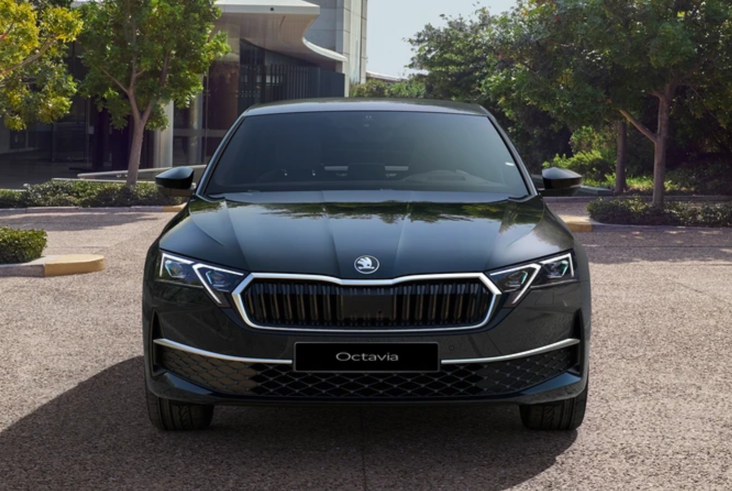 Black Skoda Octavia parked on a paved area in front of modern buildings.