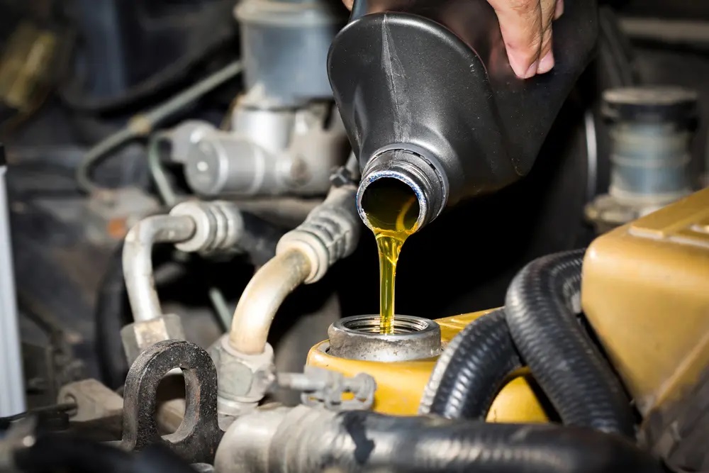 Person pouring oil into can engine tank
