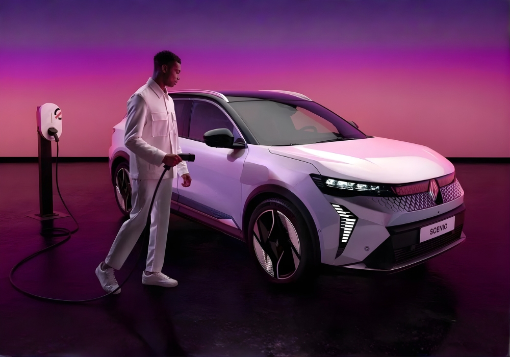 Front three-quarter view of Renault Scenic E-Tech being charged, with a person holding the charging cable.