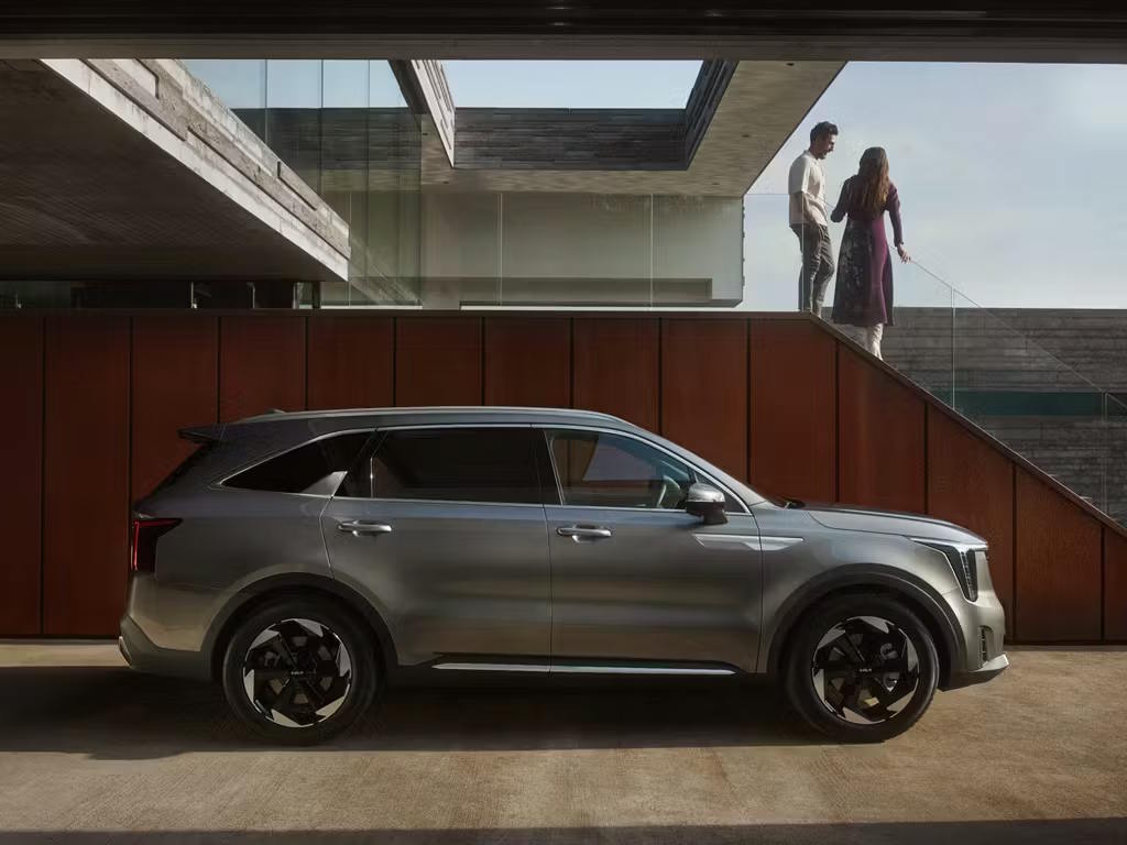 Side profile view of the Kia Sorento SUV in metallic grey, showcasing its bold shoulder line, black multi-spoke alloy wheels and distinctive LED headlight signature.