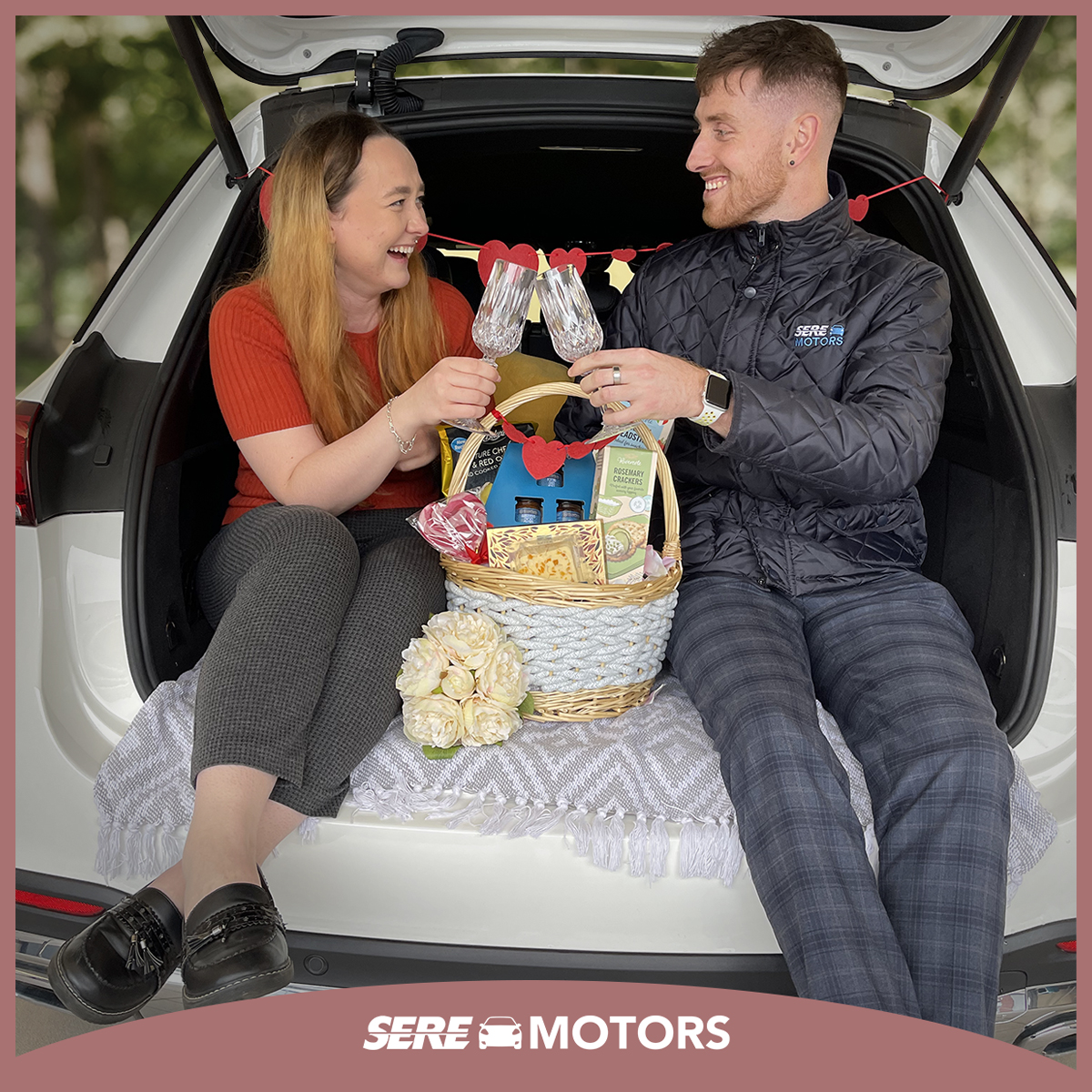 A couple enjoying a hamper in the boot of a car