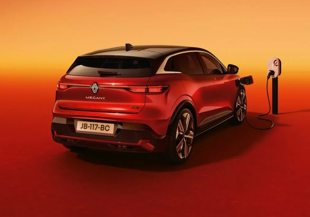 Red Renault Megane E-Tech electric SUV charging at a home charging point.