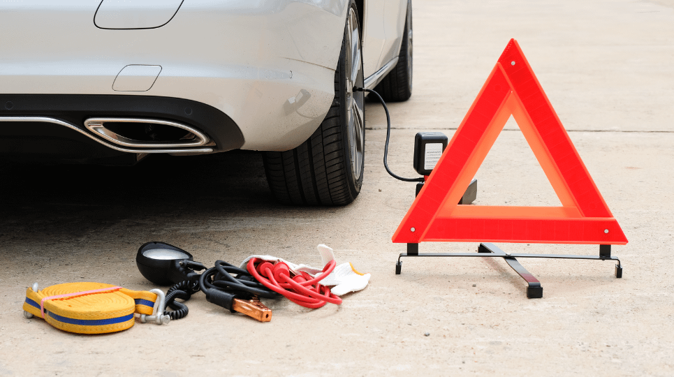roadside emergency kit beside a car with the red warning triangle