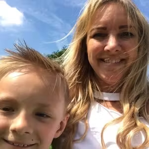 Close-up selfie of an adult and child enjoying time outside under blue skies.