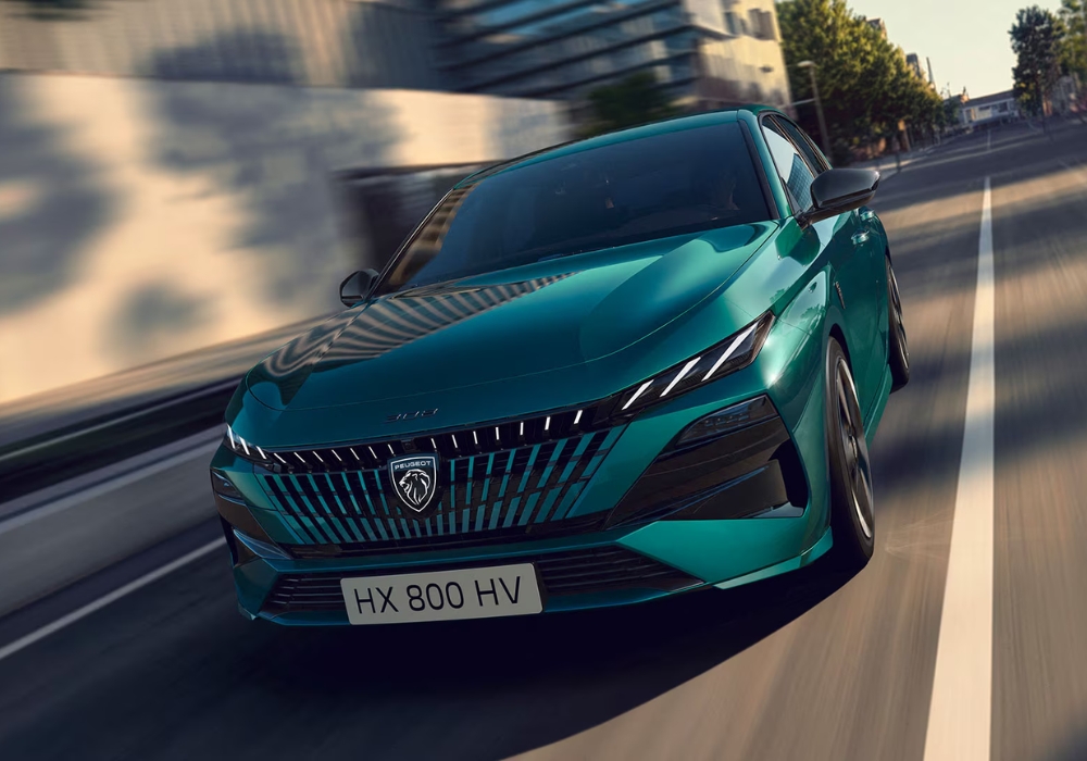 Peugeot 308 hatchback in green shown from front view driving through an urban street with motion blur.