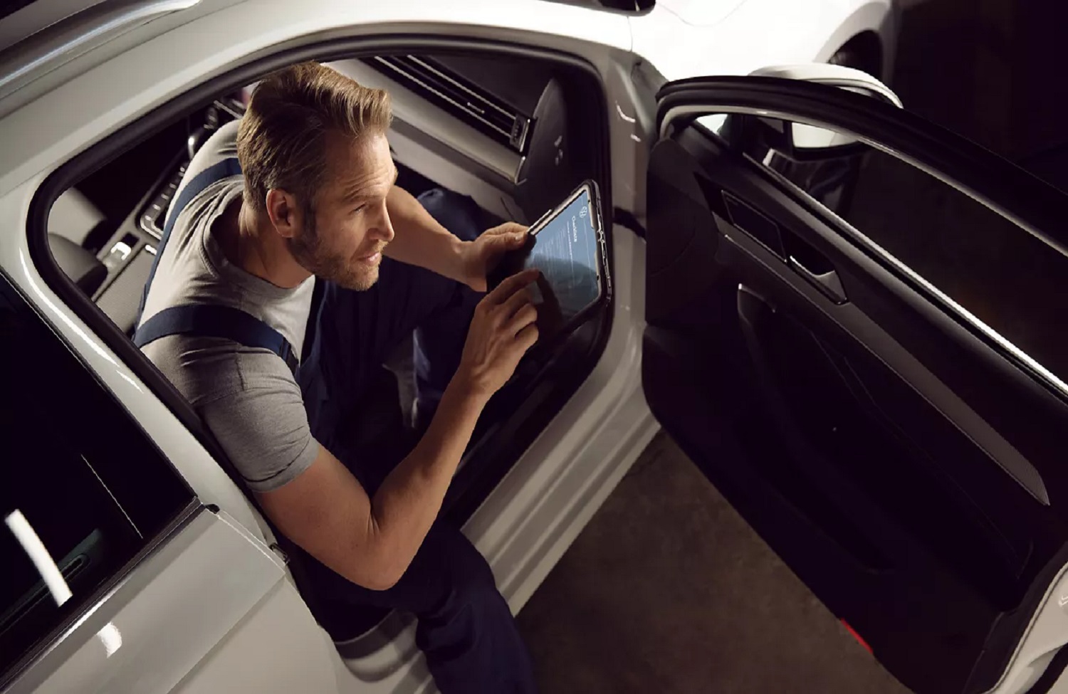 Volkswagen Mechanic Holding Tablet Sat in Vehicle
