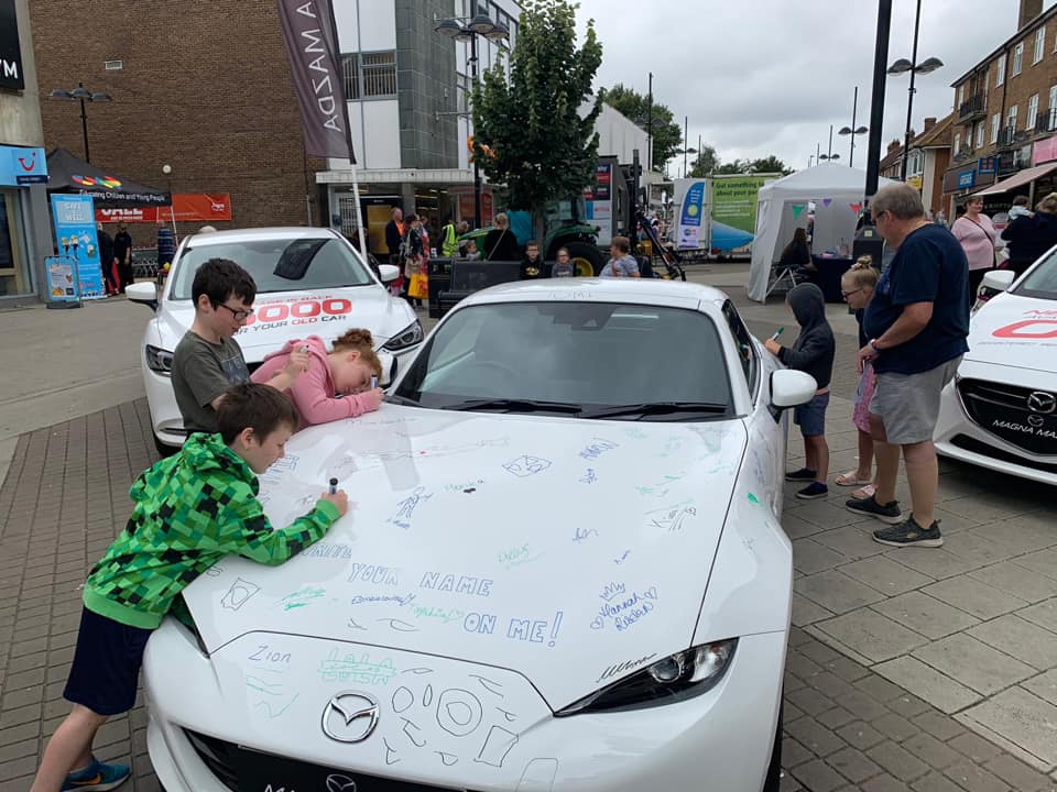 people writing on a white mazda 
