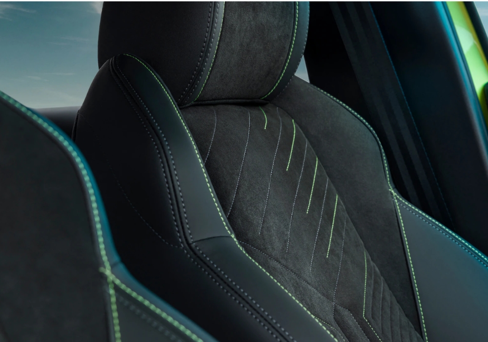 Peugeot 208 front seat detail with fabric upholstery and contrast green stitching.
