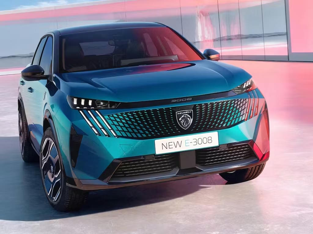 Peugeot E-3008 electric SUV in a front three-quarter view, showcasing its aerodynamic fastback silhouette, illuminated grille design and signature LED lighting.