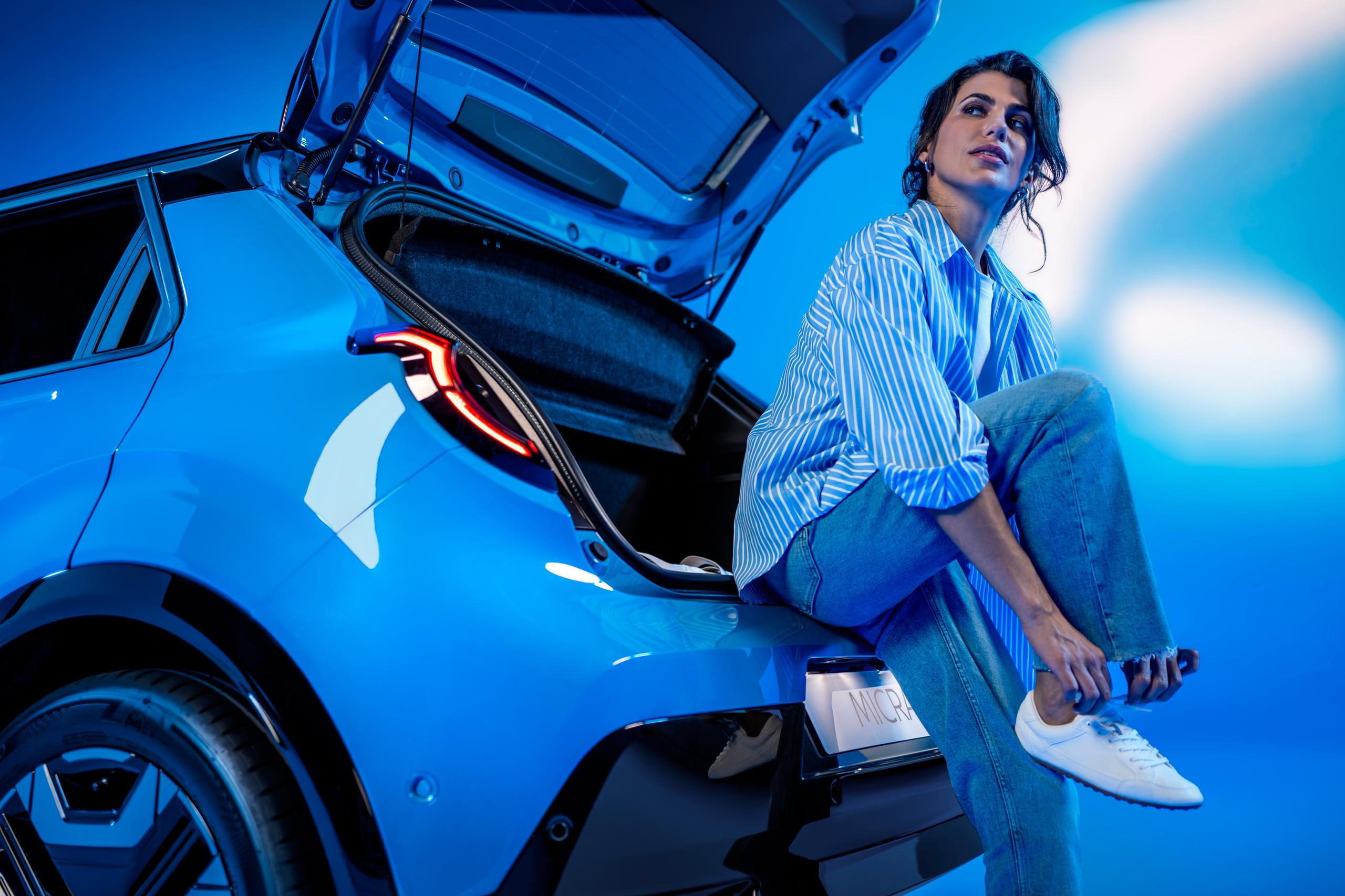 woman sat in the boot of a blue car tying her shoelace