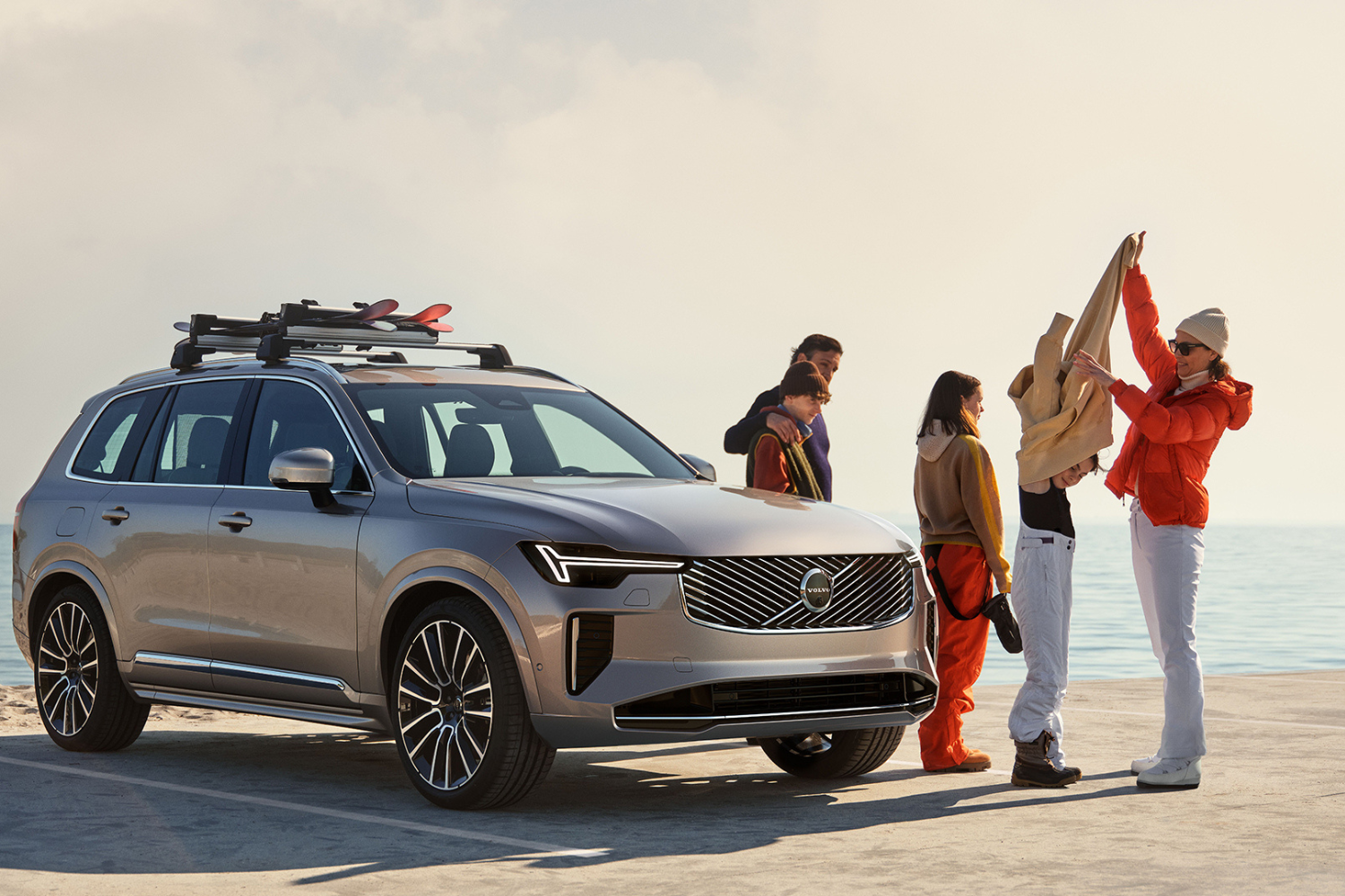 Volvo SUV parked by the sea with group preparing for outdoor trip.
