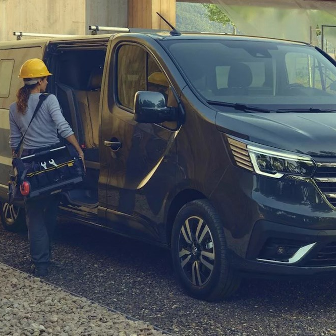 Black Renault Trafic with side door open as a person wearing a helmet and carrying tools prepares to enter the van.