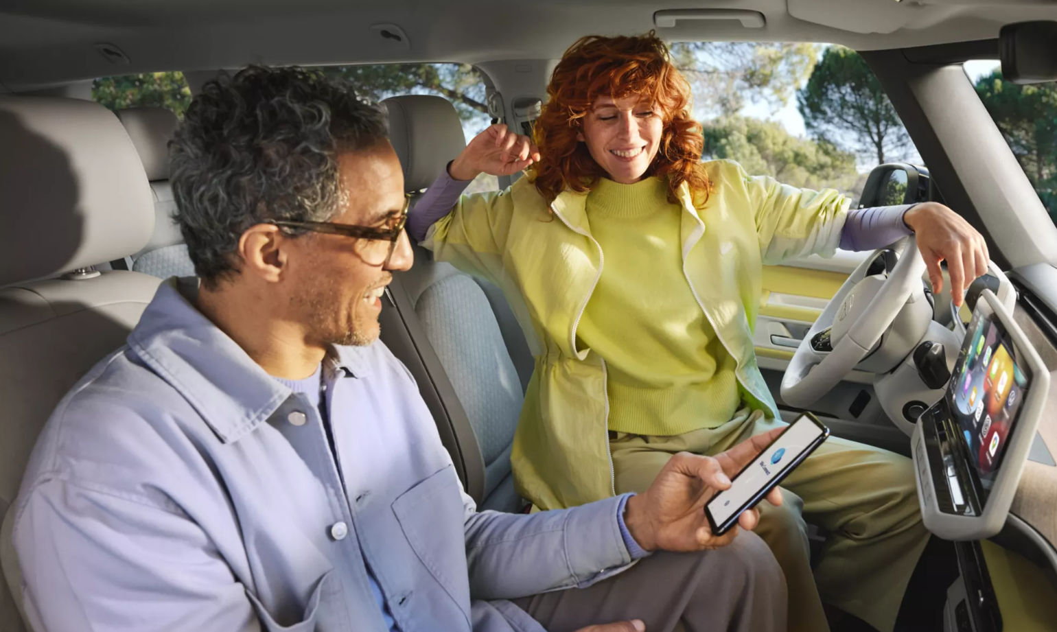 Two people in front seats of Volkswagen ID. Buzz looking at infotainment system