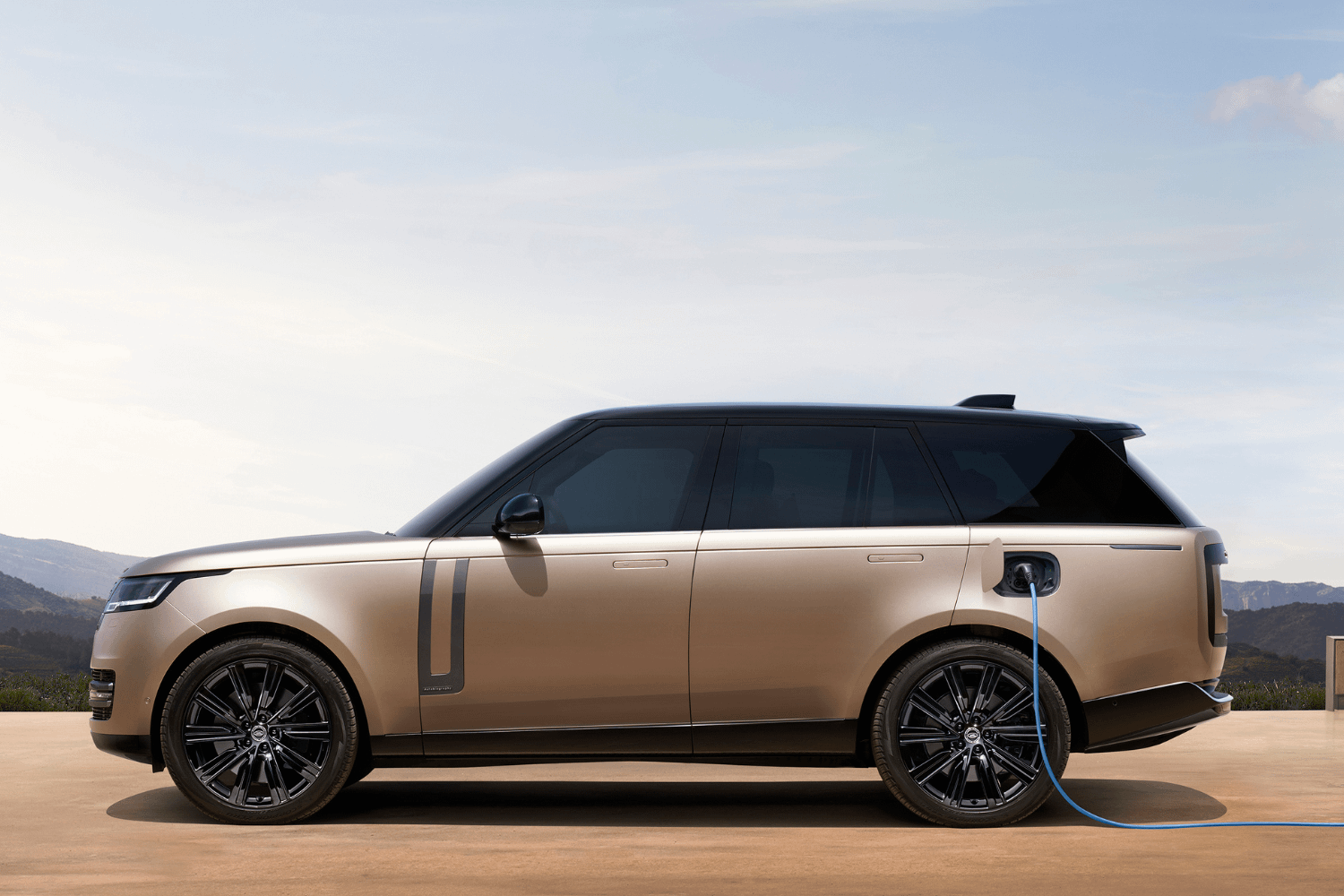 Range Rover plug-in hybrid charging with cable connected in outdoor setting.