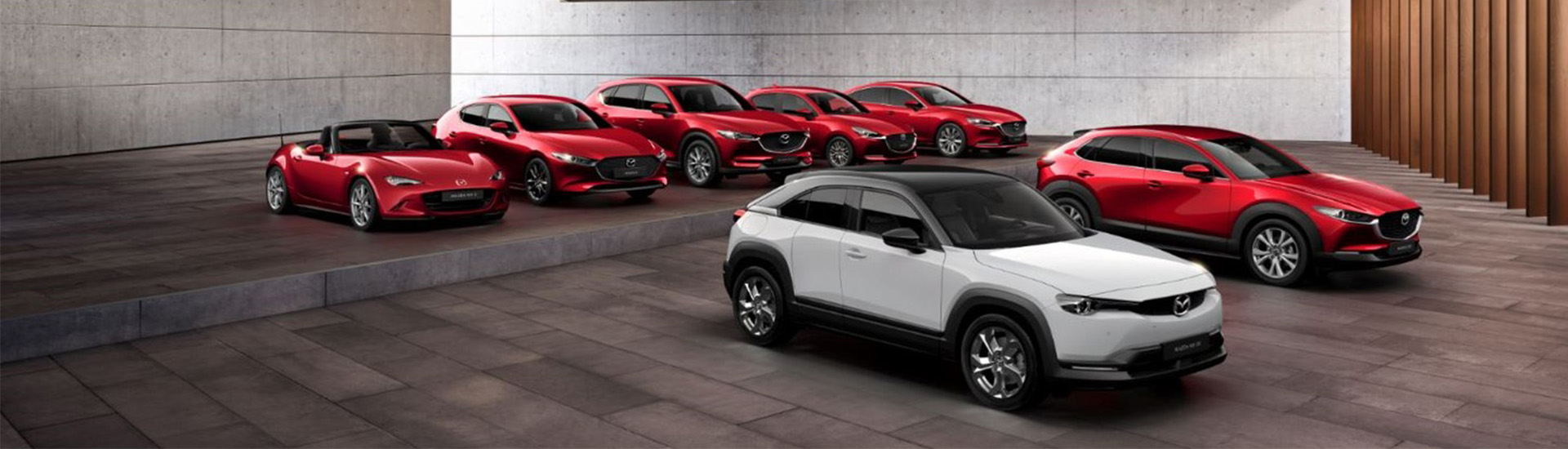 One of every Mazda car model parked next to each other.