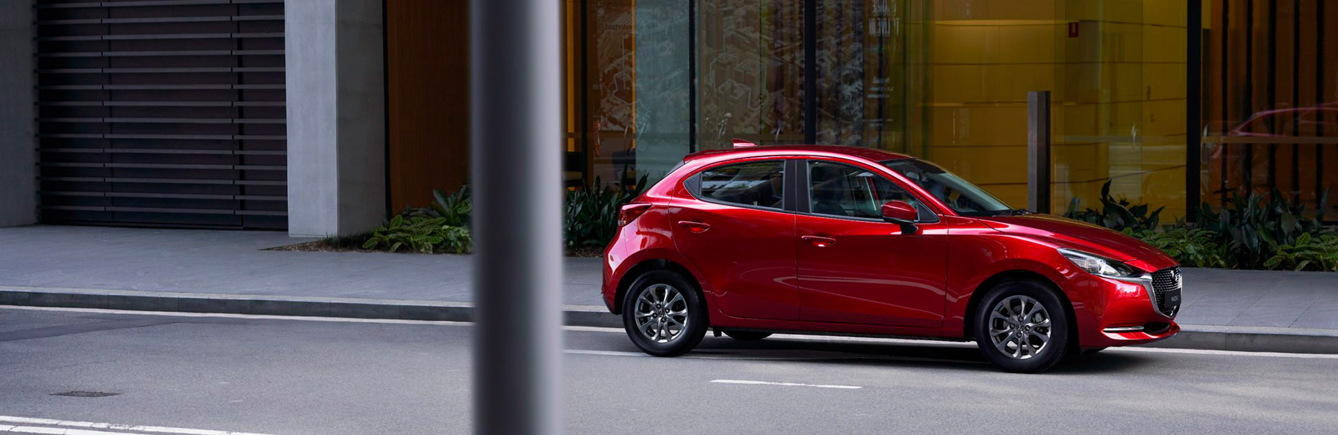 Red mazda 2 hybrid parked on an urban street