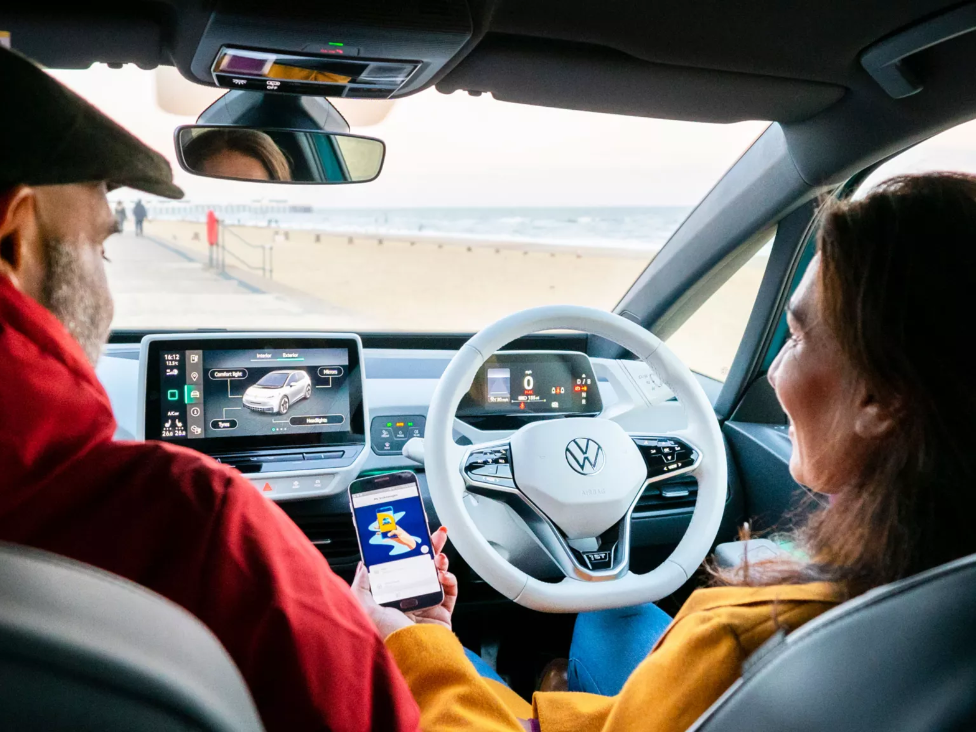 Volkswagen ID.3 Interior White Steering Wheel and Infotainment system, couple sat in front seats looking at phone