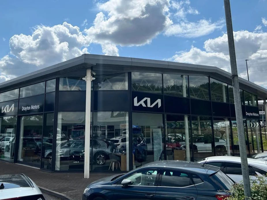 Exterior view of Drayton Motors Kia Scunthorpe showroom, featuring modern glass-fronted architecture with prominent Kia branding and new vehicles displayed in the forecourt