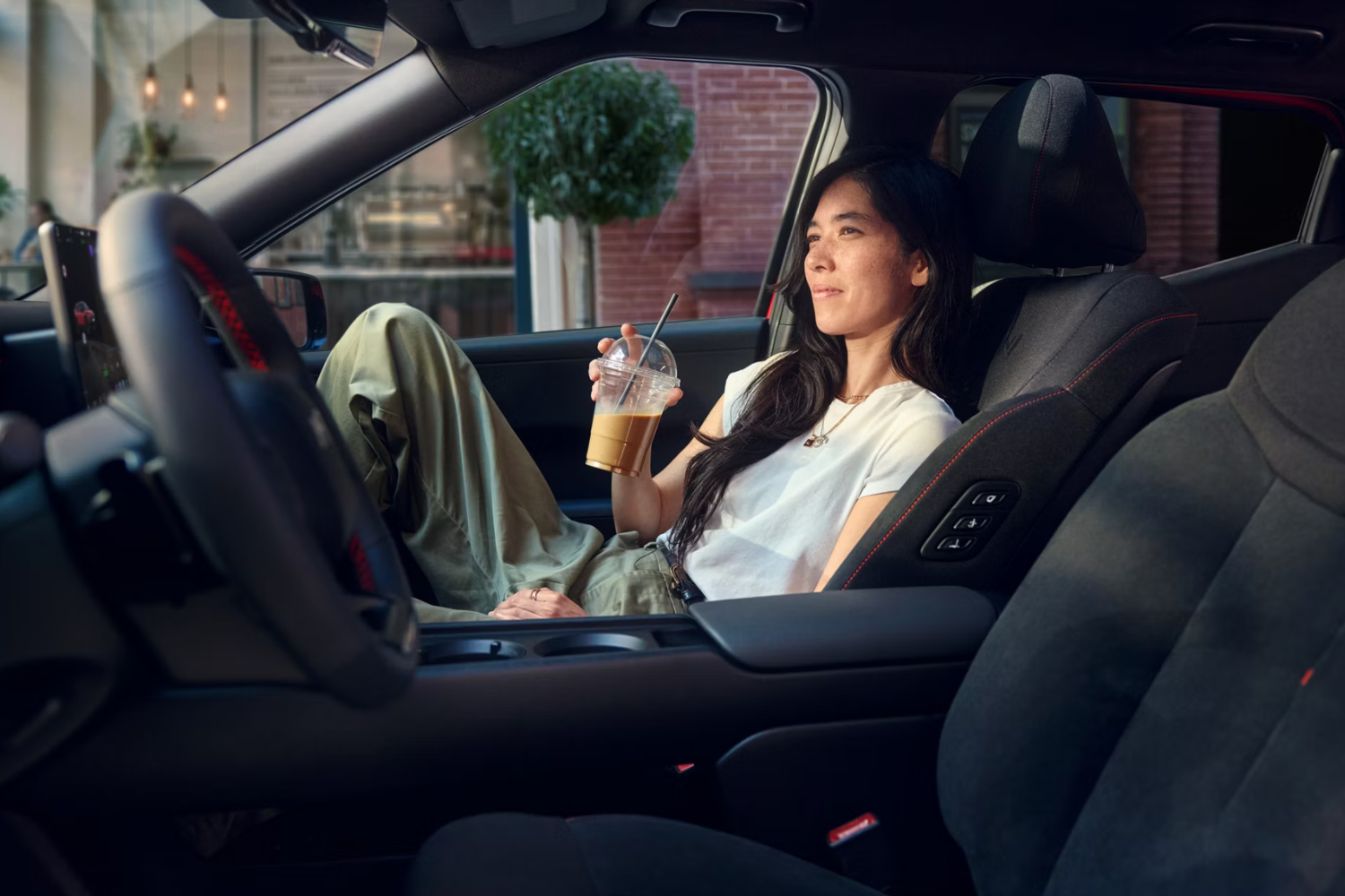 woman holding an iced coffee sat in passenger seat of New IONIQ 3