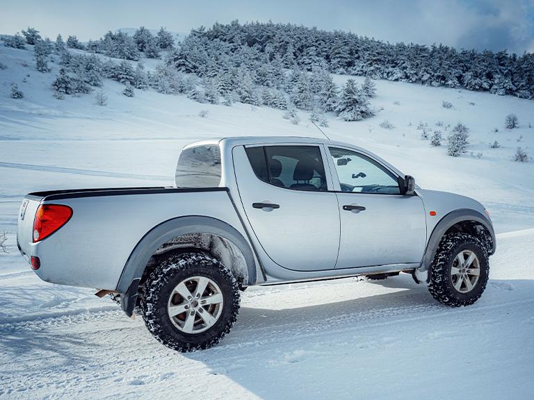 silver pickup driving in snowy conditions
