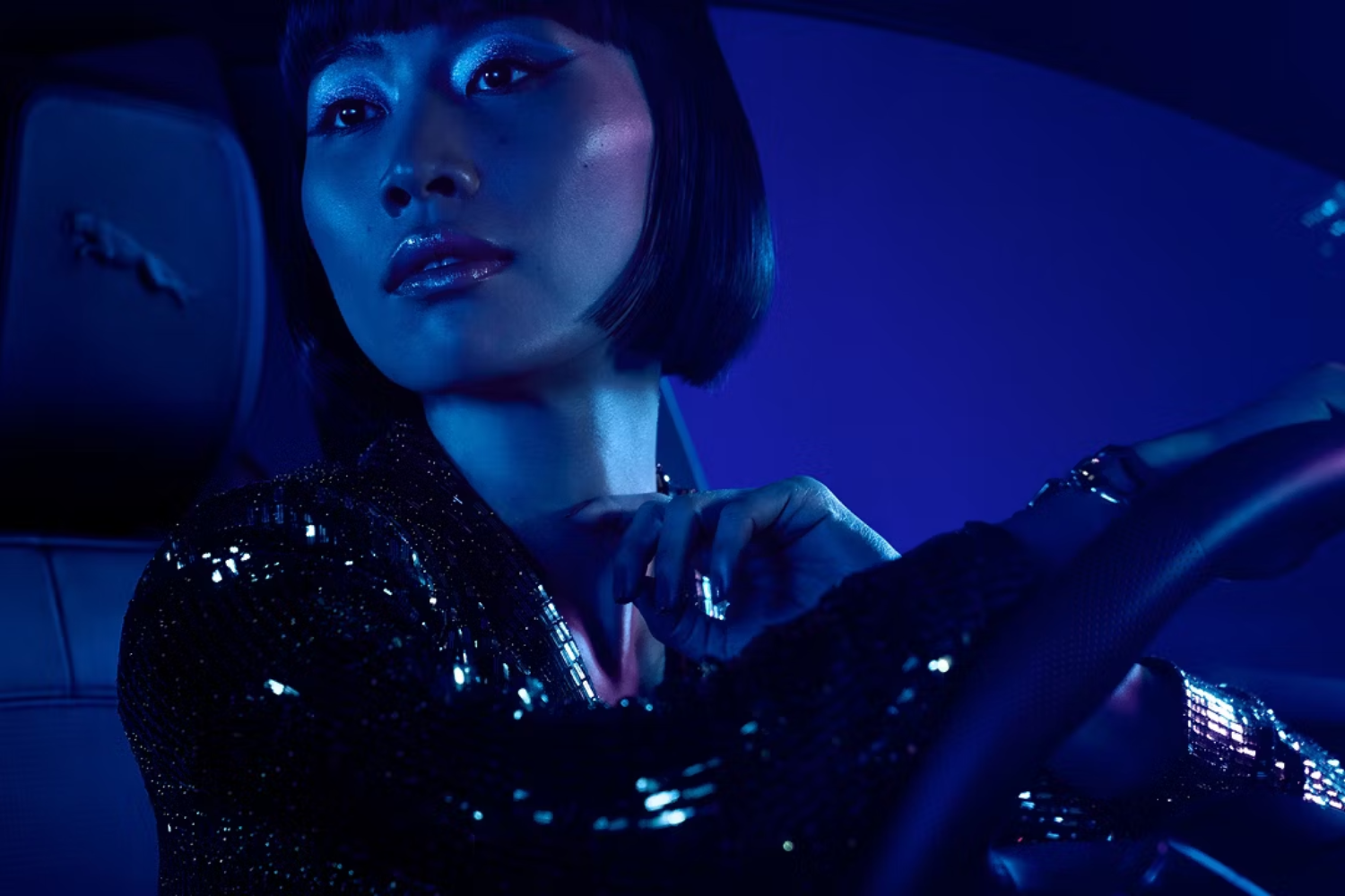 Driver seated inside luxury Jaguar interior under ambient blue lighting.