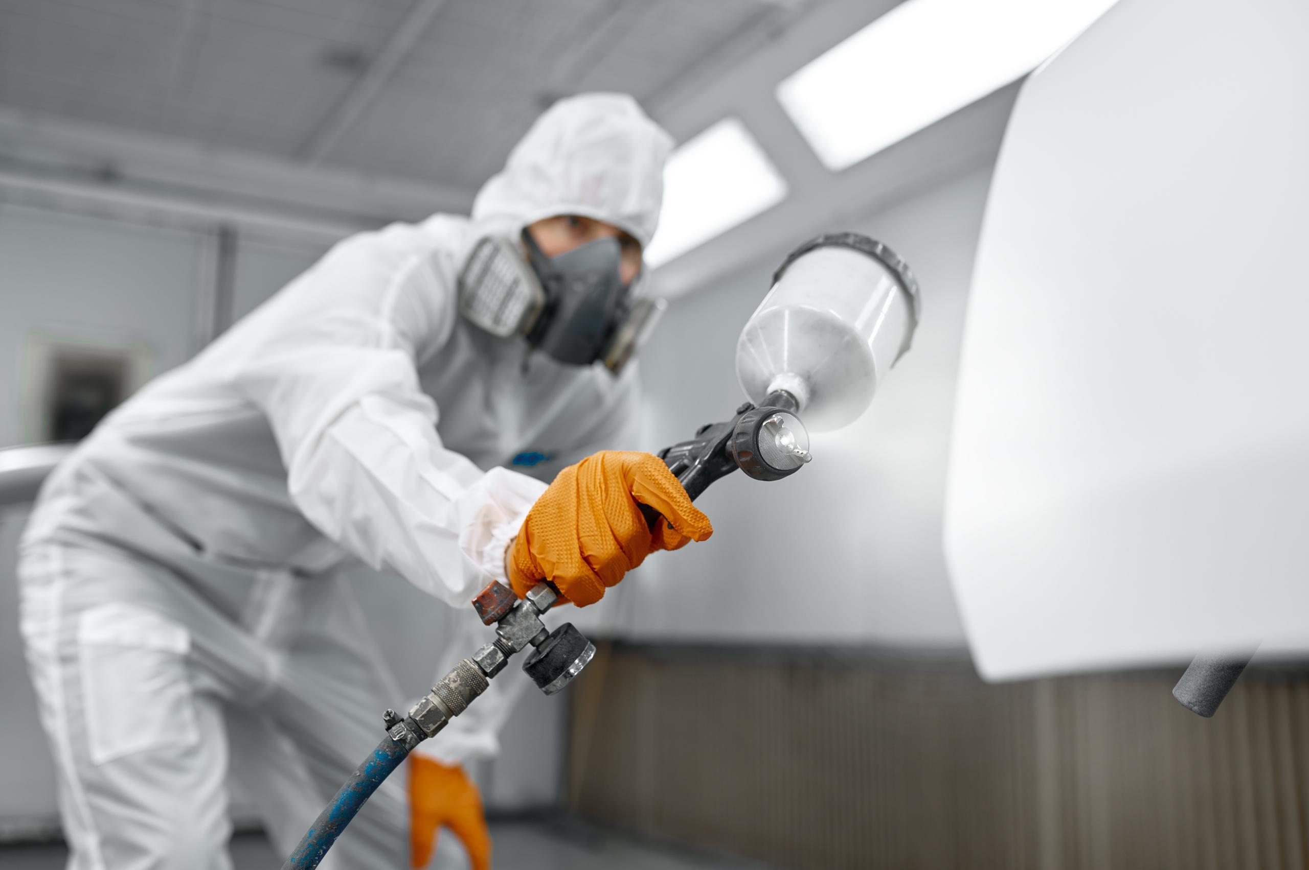 Stock photo of a cleaner in protective gear using a pressure washer.