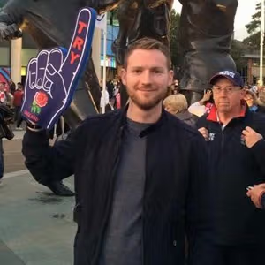 Supporter posing with a foam hand during a live sporting or entertainment event.