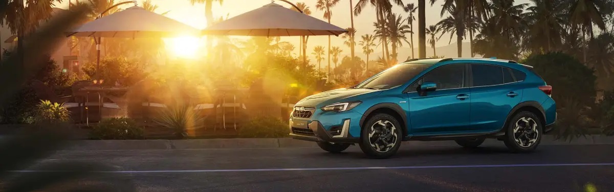 Blue Subaru XV parked on road at sunset