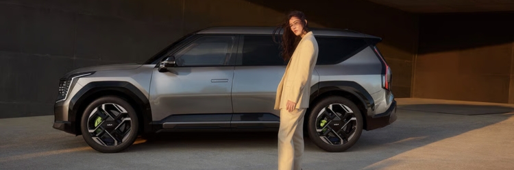 Kia EV9 GT side exterior view with a modern backdrop and a person standing nearby.